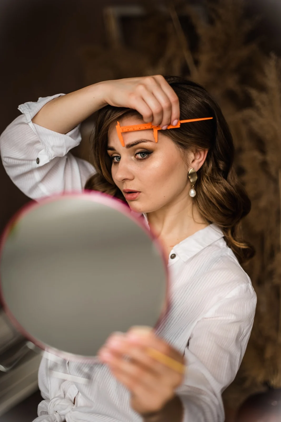 Brow mapping with an orange caliper — precise measurement before shaping