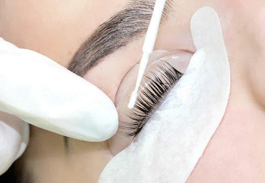 Lash lift treatment — gloved hand applying product, eye patch visible